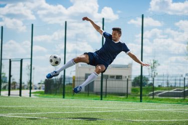 athletic-soccer-player-kicking-ball-on-soccer-pitch.jpg